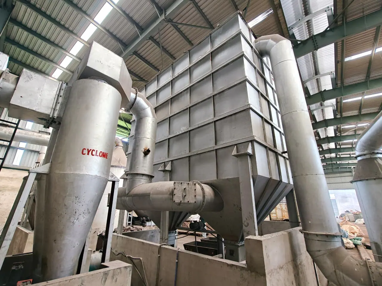 Cyclone separator and hopper-bottom bag-filter housing joined by fabricated industrial ductwork
