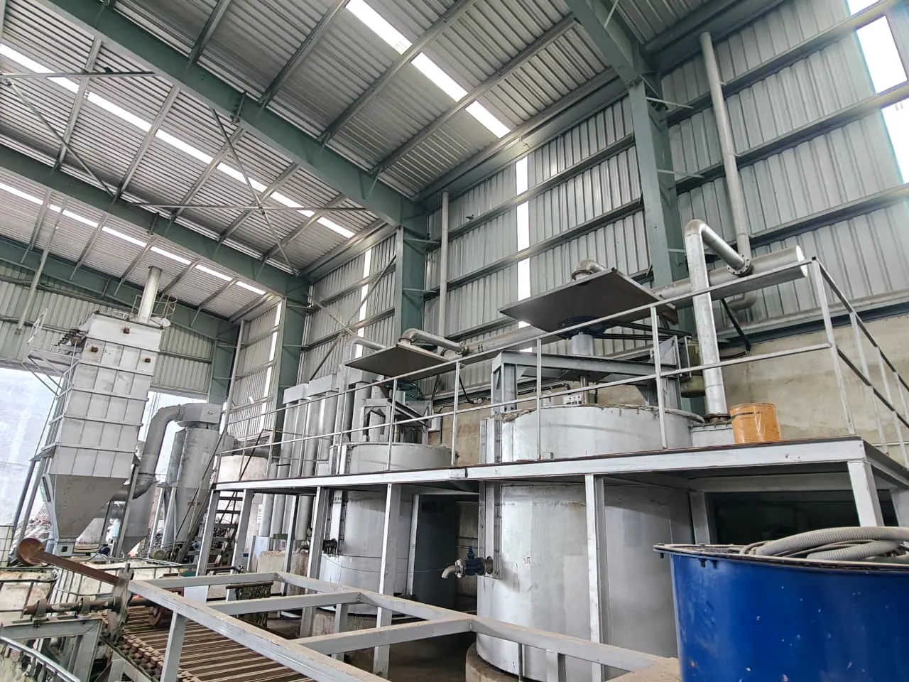 Wide workshop view of two process vessels, extraction hoods, platform, ducting and conveyor structure